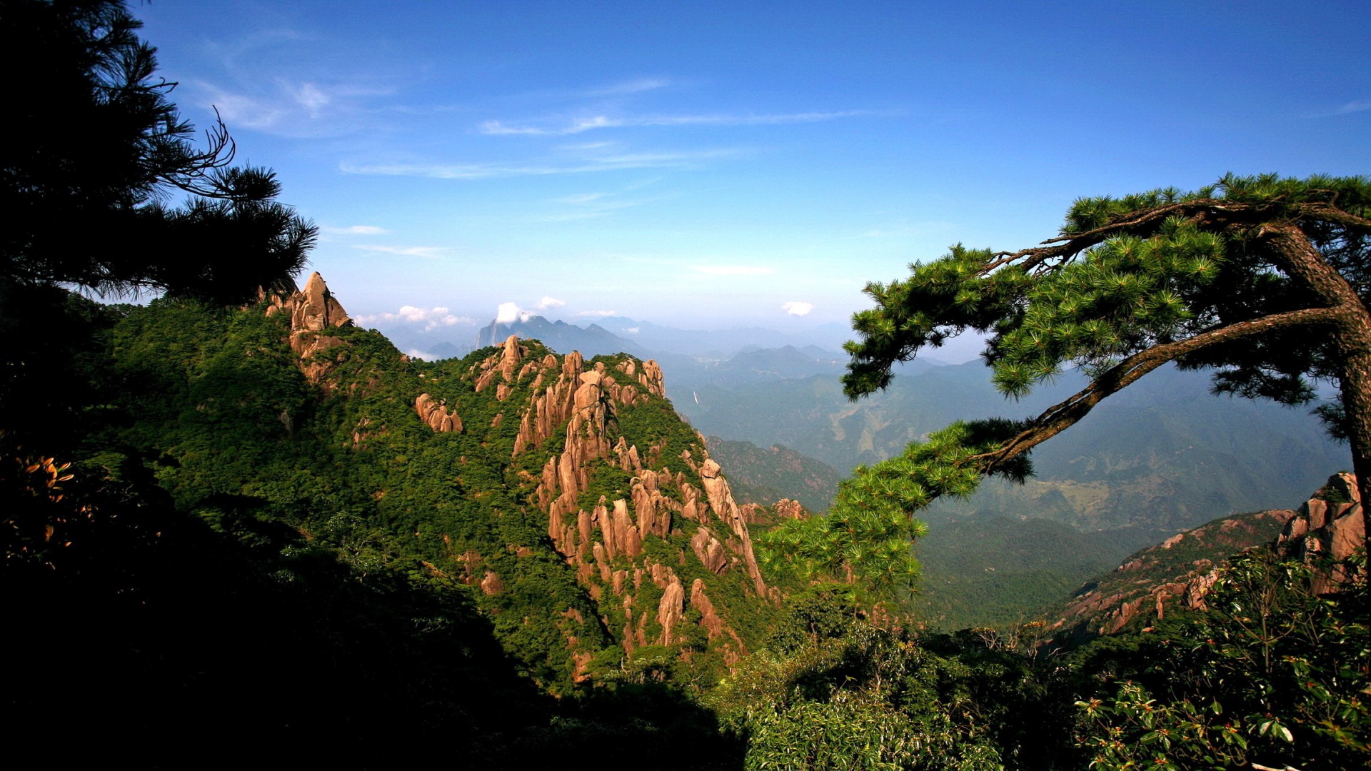 高山峻岭，岩石峭壁，山谷幽深，阳光洒落，树木葱茏，树枝交错，天空湛蓝——绝美风景桌面壁纸，免费下载，装点你的电脑屏幕！